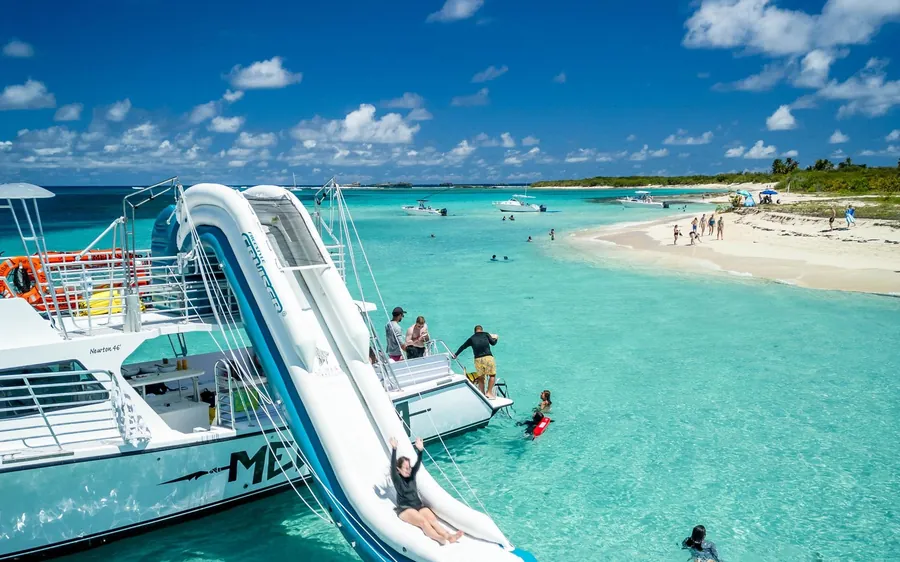 A catamaran with a white slide running down into the shallows by a sandy cay