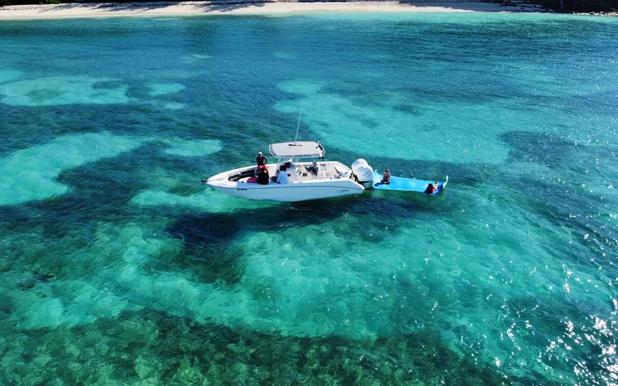 A single small boat alone on deep green-blue water, seen from the air
